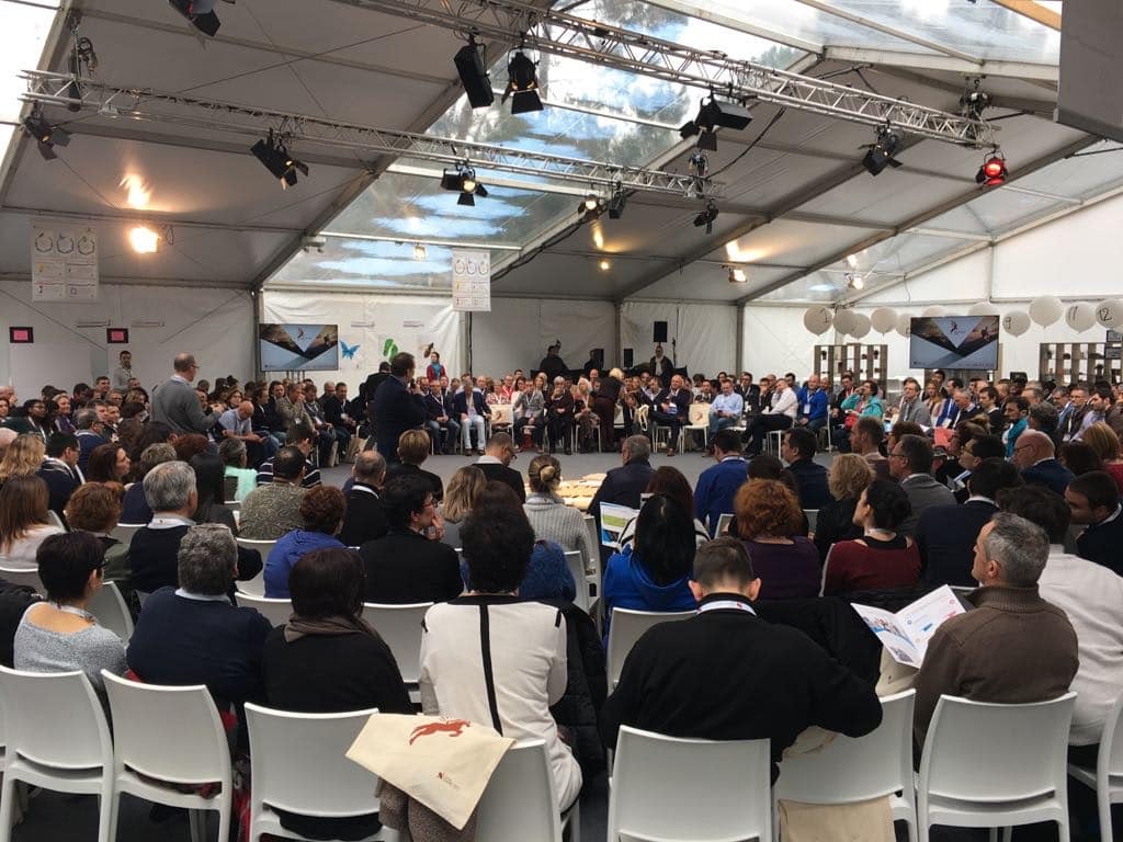 Ensemble des collaborateurs d'une organisation assis en grand cercle et écoutant une prise de parole